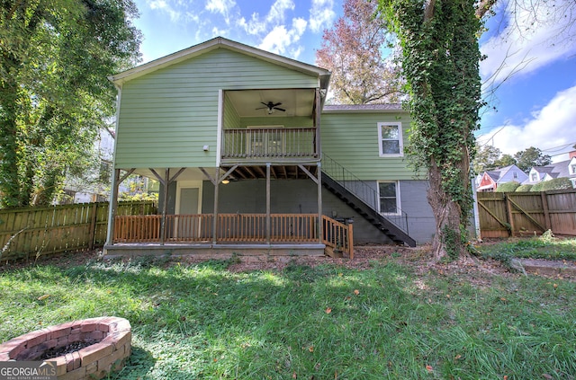 back of property with a lawn, ceiling fan, and an outdoor fire pit