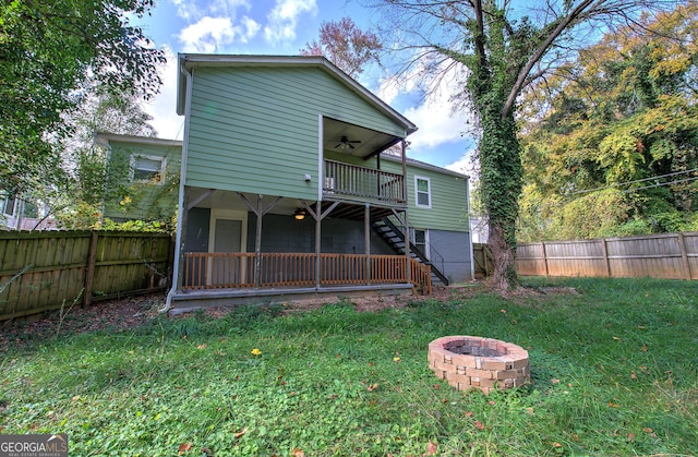 back of property with a lawn, ceiling fan, and an outdoor fire pit