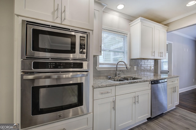 kitchen with decorative backsplash, light stone countertops, stainless steel appliances, sink, and white cabinetry