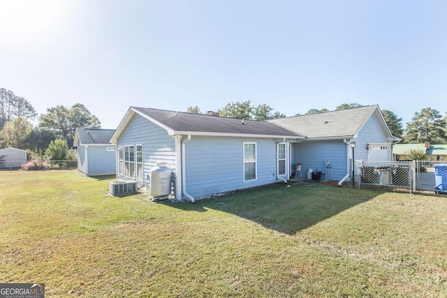 rear view of property with central air condition unit and a yard