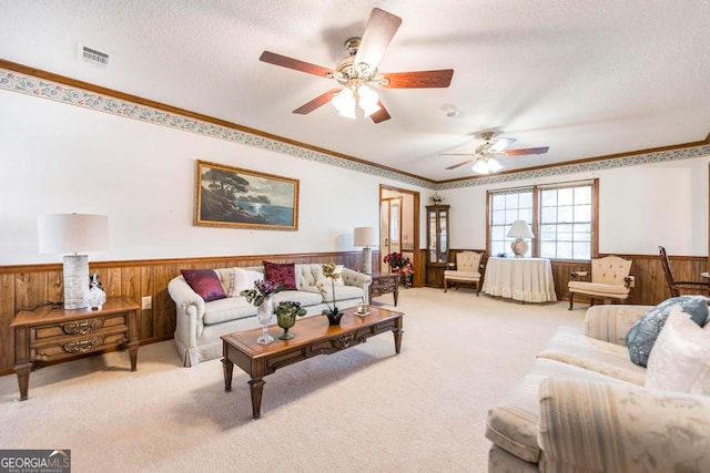 living room featuring a textured ceiling, light colored carpet, wooden walls, and ceiling fan