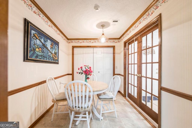 dining area with french doors, a textured ceiling, and crown molding