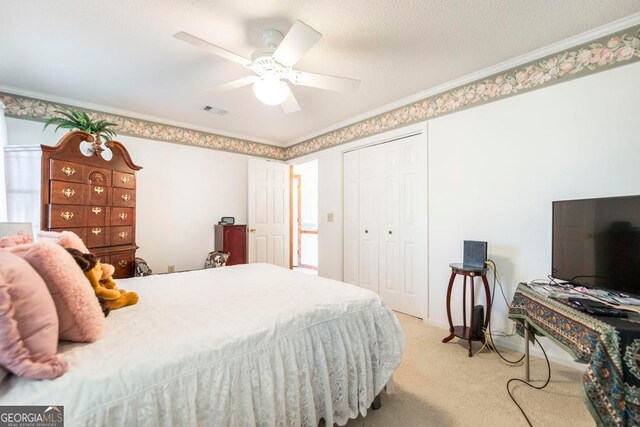 bedroom featuring ornamental molding, a closet, light carpet, and ceiling fan