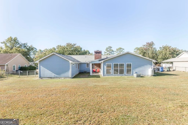 rear view of property with central air condition unit and a yard