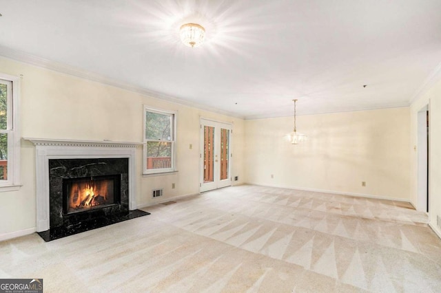 unfurnished living room featuring a premium fireplace, light carpet, crown molding, and an inviting chandelier