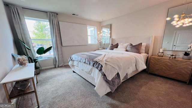 carpeted bedroom with multiple windows and an inviting chandelier