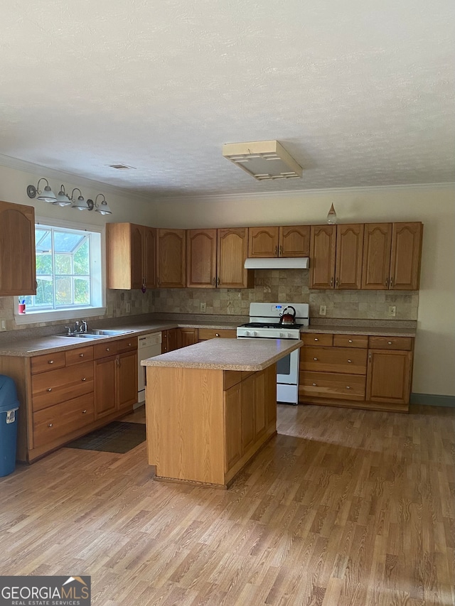 kitchen with a center island, sink, backsplash, light hardwood / wood-style flooring, and white appliances