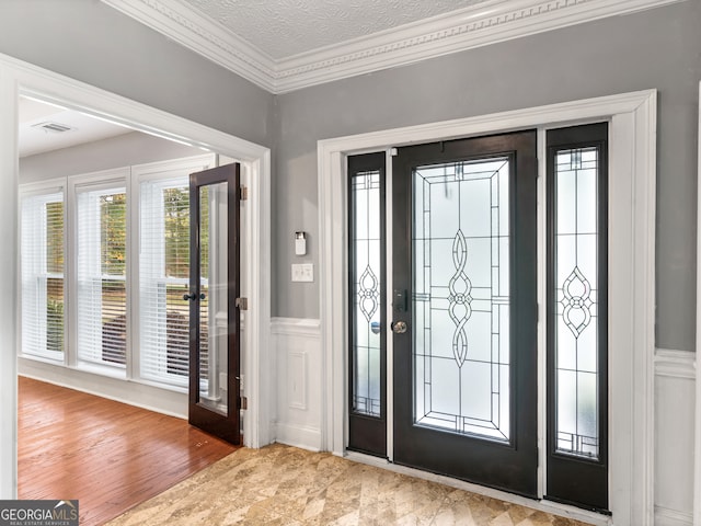 entrance foyer with a textured ceiling, light hardwood / wood-style flooring, and crown molding