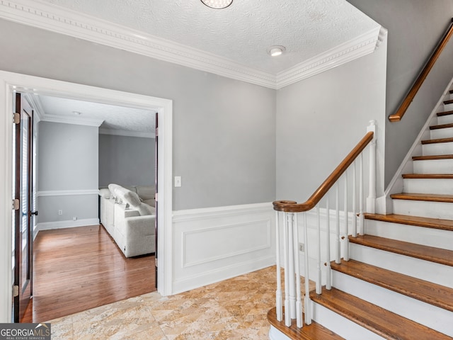 stairs with hardwood / wood-style floors, a textured ceiling, and crown molding