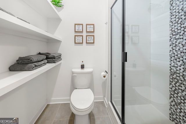 bathroom featuring tile patterned floors, toilet, and a shower with shower door