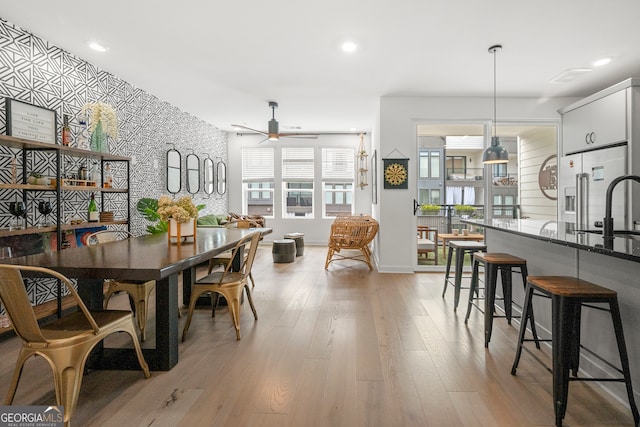 dining area featuring ceiling fan, light wood-type flooring, and sink