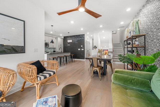 living room with ceiling fan, light hardwood / wood-style flooring, and sink