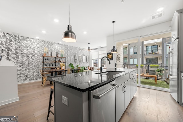 kitchen with a center island with sink, white cabinetry, stainless steel dishwasher, and sink