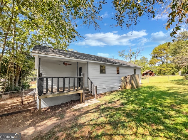 rear view of house featuring ceiling fan and a yard