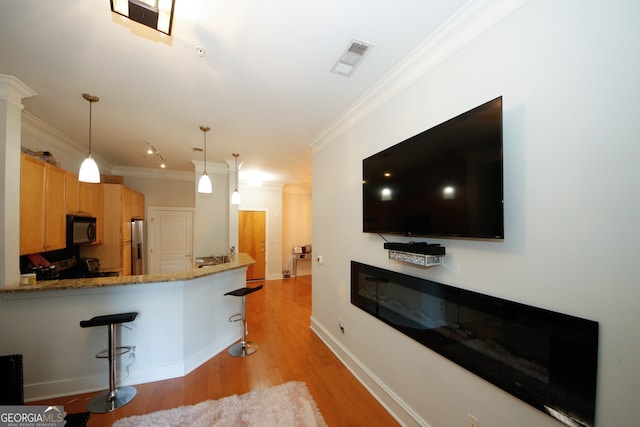 kitchen featuring black appliances, crown molding, a breakfast bar, light hardwood / wood-style floors, and kitchen peninsula