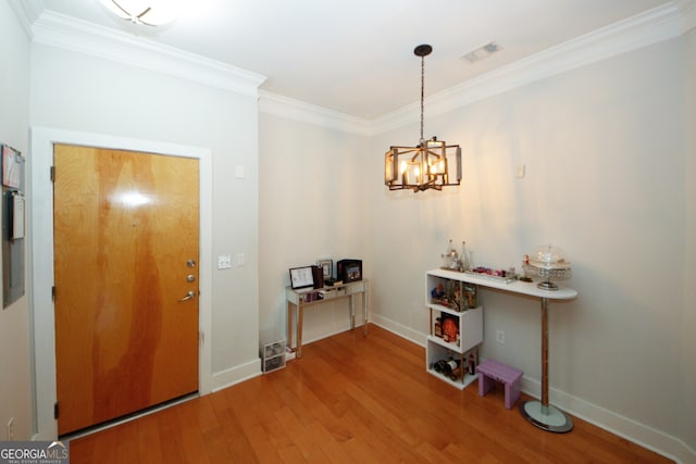 entrance foyer with a chandelier, wood-type flooring, and crown molding