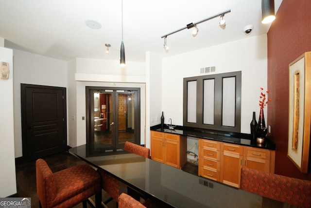 bar featuring hanging light fixtures, sink, and track lighting