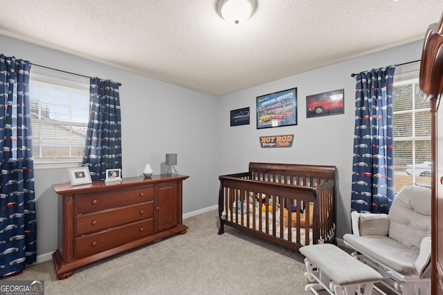 carpeted bedroom featuring a crib and a textured ceiling