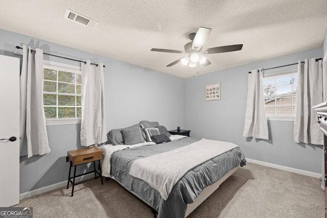 bedroom with multiple windows, a textured ceiling, light carpet, and ceiling fan