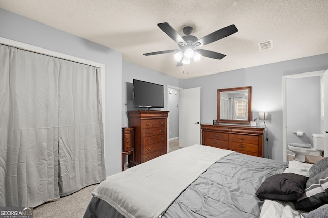 carpeted bedroom with ceiling fan, ensuite bathroom, and a textured ceiling