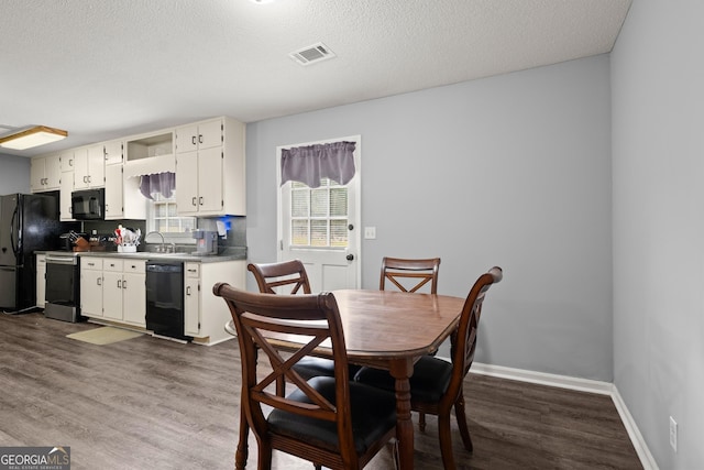 dining area with sink, dark hardwood / wood-style floors, and a textured ceiling