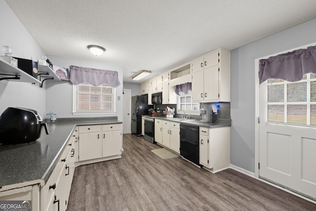 kitchen with white cabinetry, sink, black appliances, a textured ceiling, and light hardwood / wood-style flooring