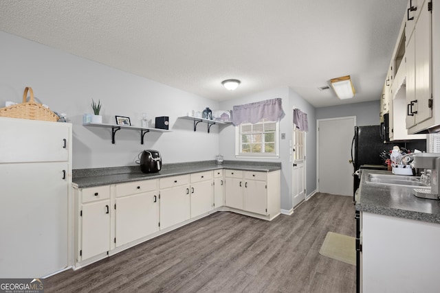 kitchen featuring hardwood / wood-style flooring, sink, white cabinets, and a textured ceiling