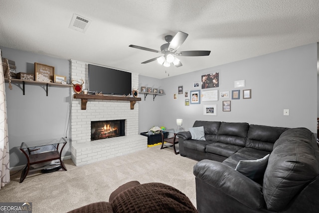 carpeted living room with ceiling fan, a brick fireplace, and a textured ceiling