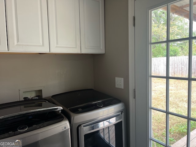 clothes washing area featuring cabinets and washing machine and clothes dryer