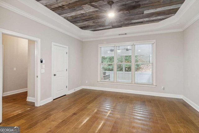 spare room with wood-type flooring, a raised ceiling, and crown molding