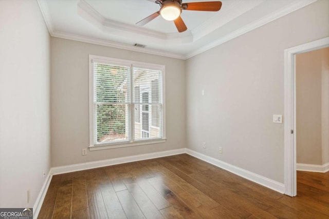 empty room featuring a tray ceiling, ceiling fan, dark wood-type flooring, and crown molding