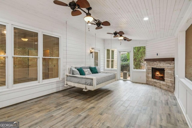 sunroom with a fireplace, wooden ceiling, and ceiling fan