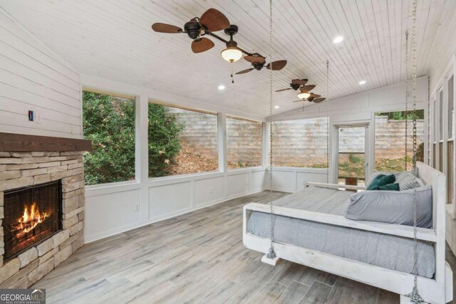 sunroom with lofted ceiling, ceiling fan, wooden ceiling, and a fireplace