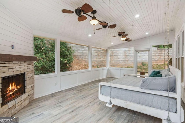 sunroom with a stone fireplace, vaulted ceiling, and wooden ceiling