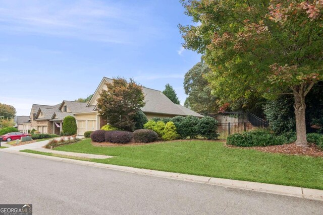 view of property hidden behind natural elements with a garage and a front lawn