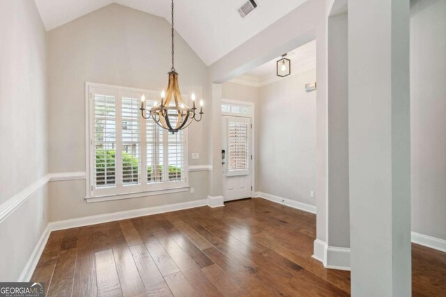 entryway featuring vaulted ceiling, dark wood-type flooring, and an inviting chandelier