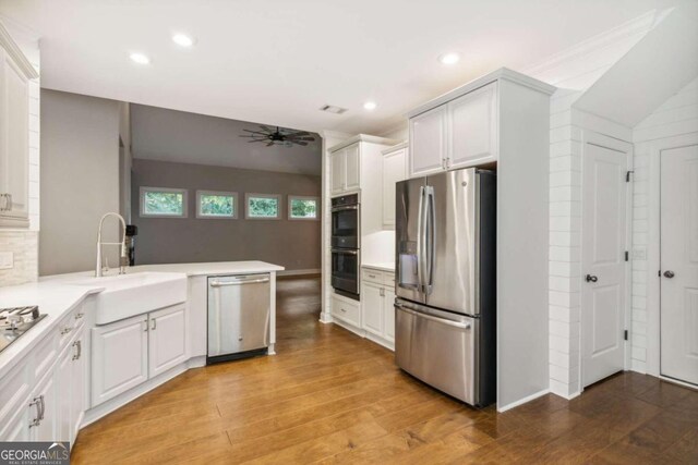 kitchen featuring kitchen peninsula, appliances with stainless steel finishes, ceiling fan, sink, and white cabinetry