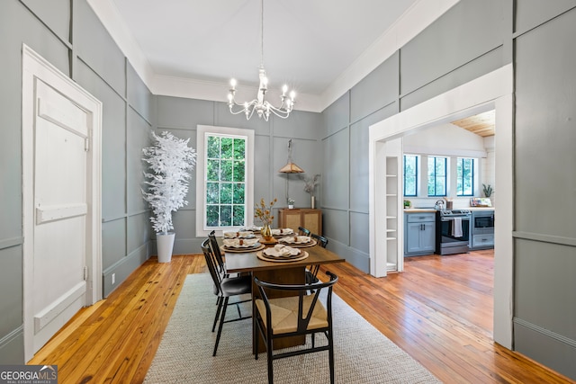 dining area with an inviting chandelier, light hardwood / wood-style flooring, a wealth of natural light, and ornamental molding