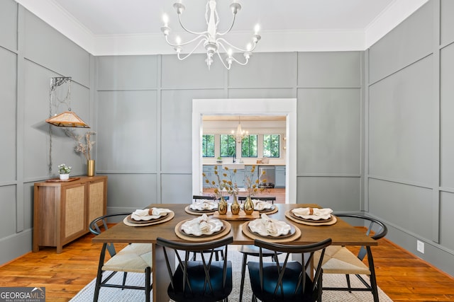 dining room featuring a chandelier, light wood-type flooring, and crown molding