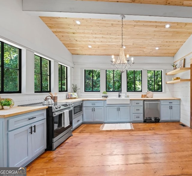 kitchen with vaulted ceiling with beams, decorative light fixtures, sink, and appliances with stainless steel finishes