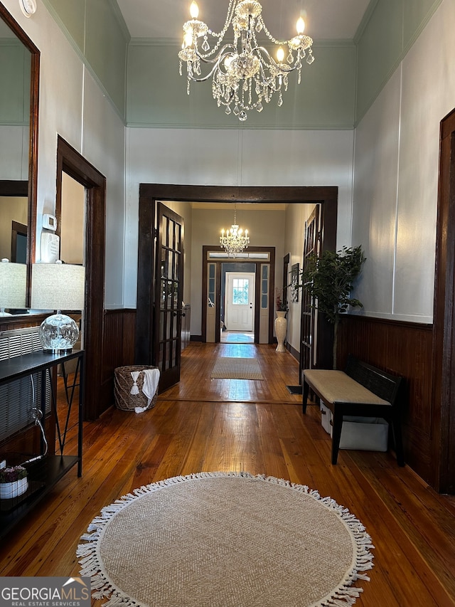 entrance foyer featuring wood-type flooring, crown molding, and a notable chandelier