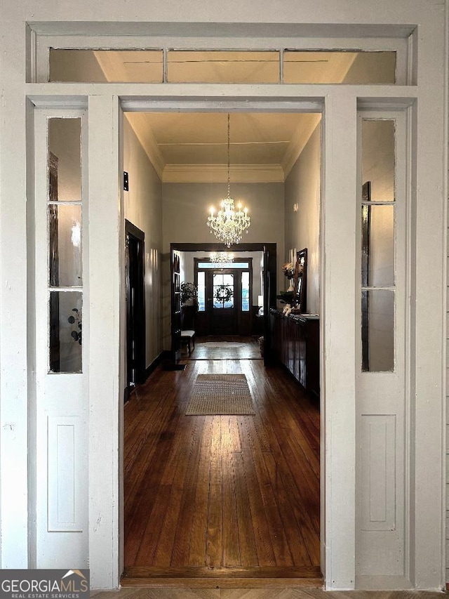 hall with a chandelier, ornamental molding, and dark wood-type flooring