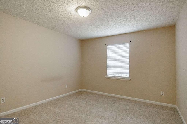 spare room with light colored carpet and a textured ceiling