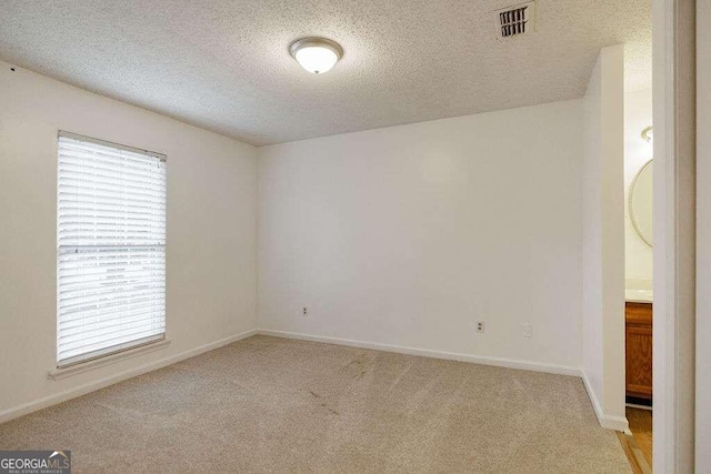 carpeted empty room with a textured ceiling