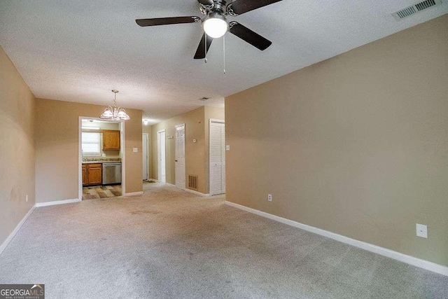 carpeted empty room featuring a textured ceiling and ceiling fan with notable chandelier