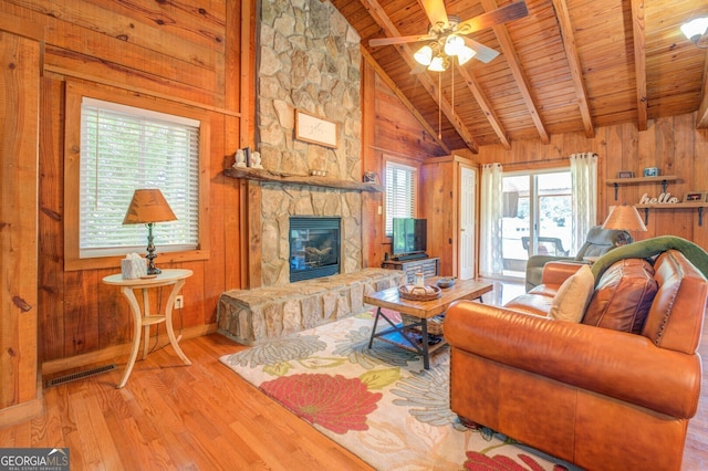 living room featuring light wood-type flooring, a fireplace, lofted ceiling with beams, and wooden walls