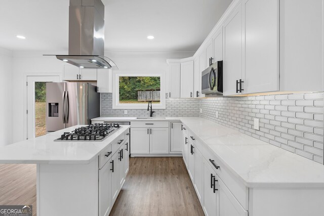 kitchen featuring white cabinetry, sink, light stone counters, appliances with stainless steel finishes, and island exhaust hood