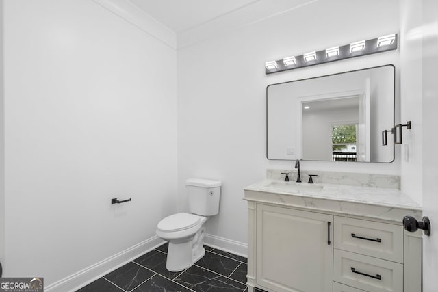 bathroom with toilet, vanity, and ornamental molding