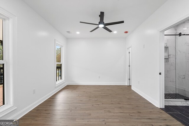 unfurnished room featuring dark hardwood / wood-style flooring, a barn door, and ceiling fan