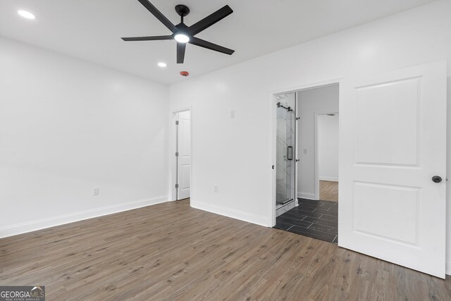 unfurnished bedroom featuring dark hardwood / wood-style floors, ceiling fan, and connected bathroom